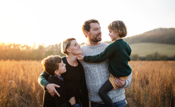 A beautiful young family with small children on a walk in autumn nature, talking.