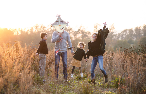 A beautiful young family with small children on a walk in autumn nature, having fun.