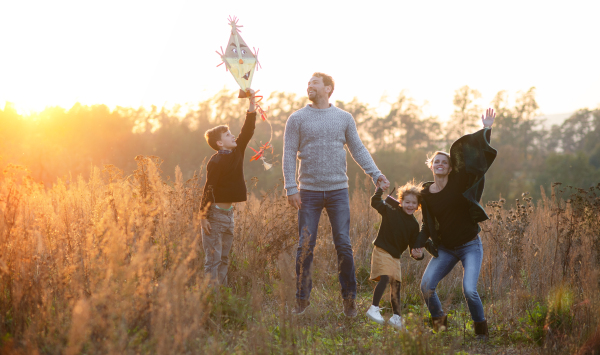 A beautiful young family with small children on a walk in autumn nature, having fun.