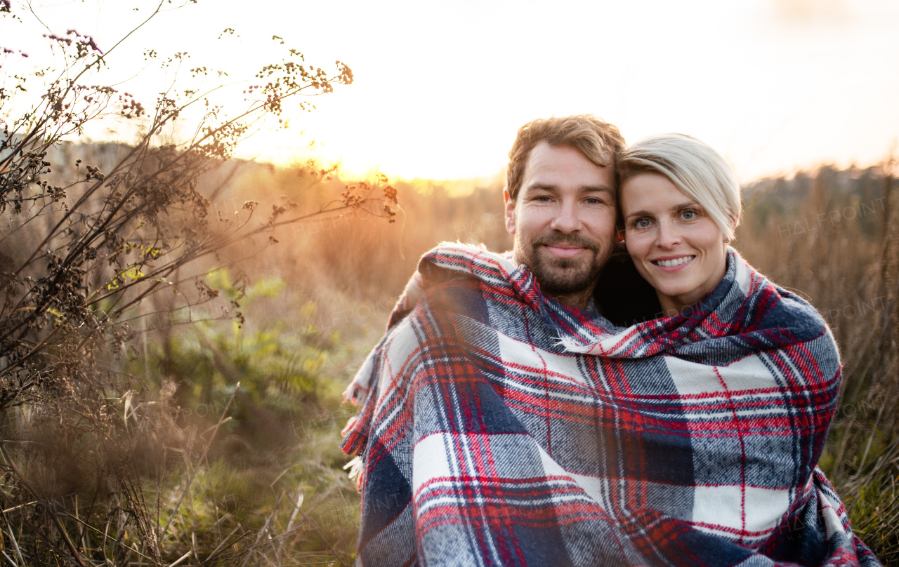 Portrait of young couple in love on a walk in autumn nature, looking at camera.