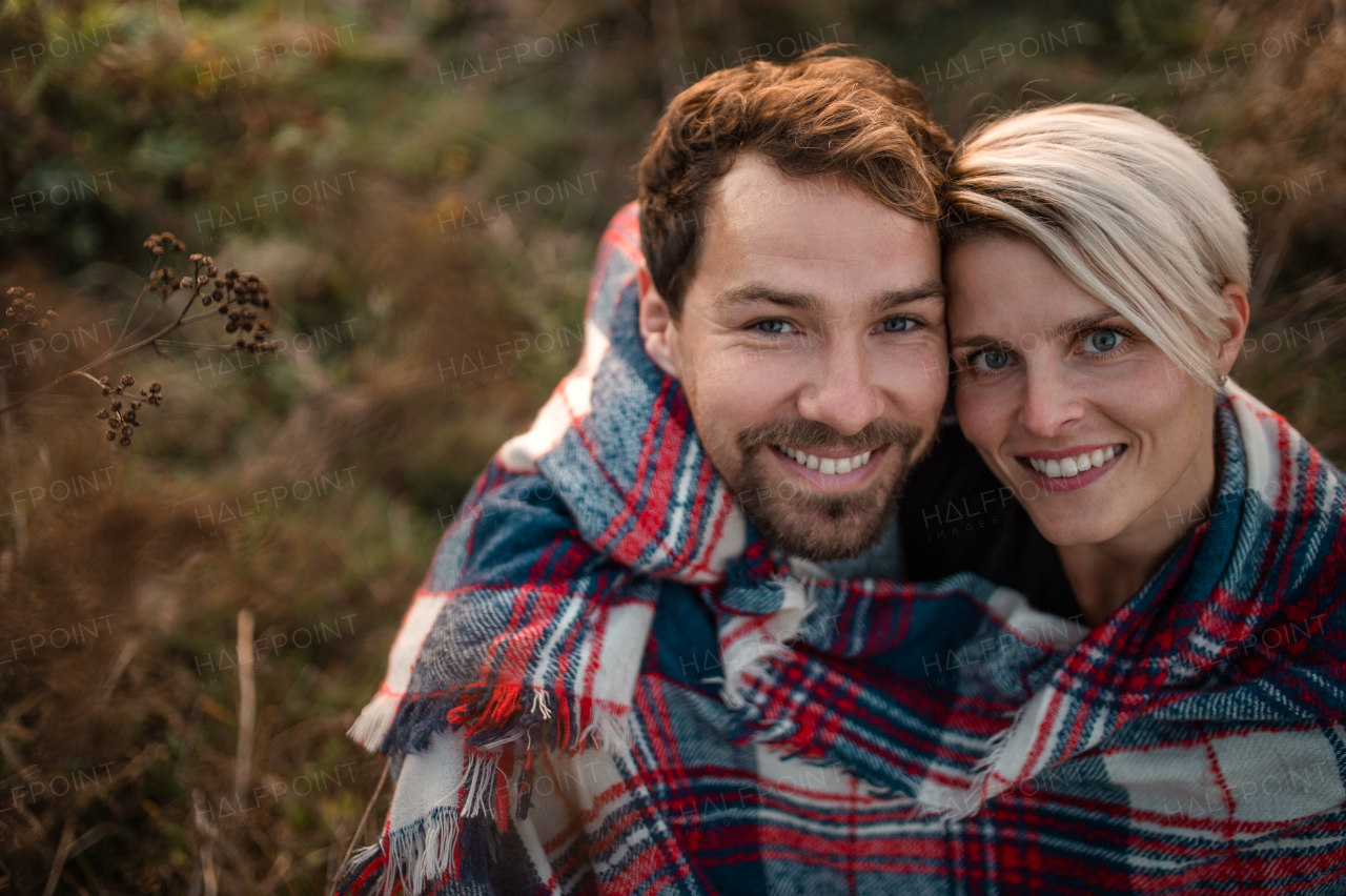 Top view of young couple in love on a walk in autumn nature, looking at camera.