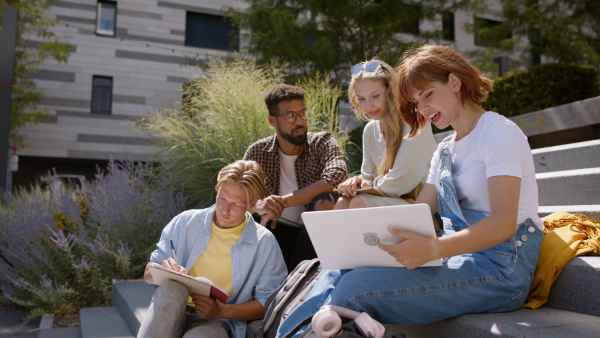 A group of students sitting on staircase, talking about school project.