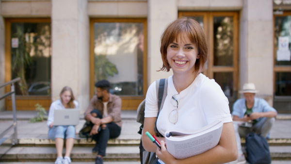 Young female student preparing for exam in front of the university building.