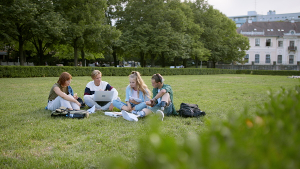 A group of students sitting in park, talking about school project, leg prosthetic concept.