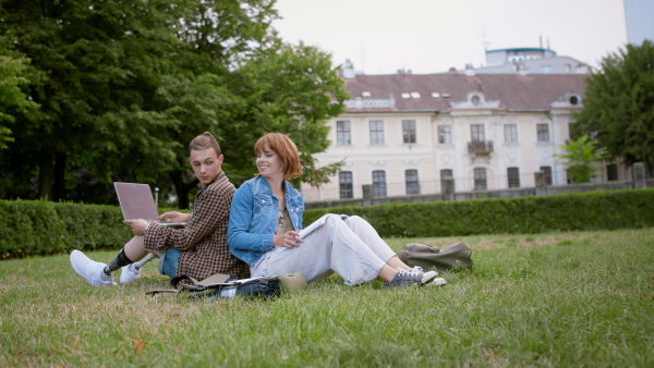 Young student couple sitting in park, working on school project, leg prosthetic concept.