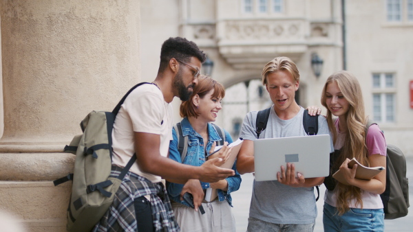 A group of students meeting in front of the university building, talking about school project.