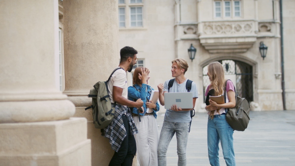 A group of students meeting in front of the university building, celebrating after getting results of exams.