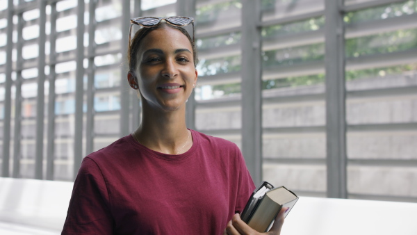 Young female arabic university student standing in corridor indoors, looking at camera.