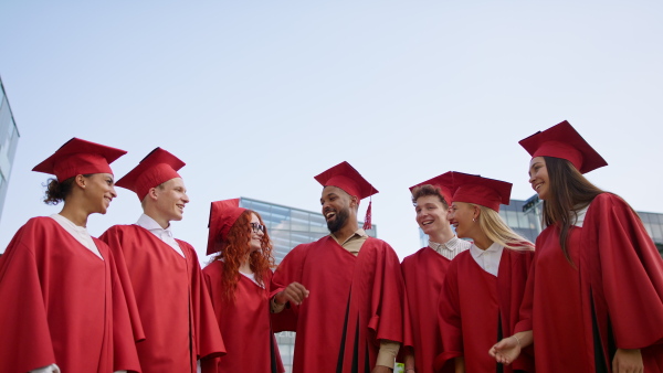 A group of cheerful university students celebrating outdoors, graduation concept.