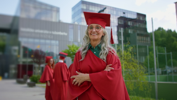 A cheerful senior woman student outdoors, graduation and third age university concept.