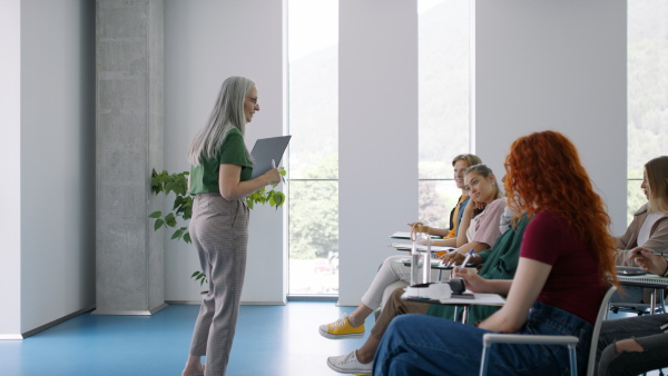 University students with a teacher studying indoors, lesson in classroom.