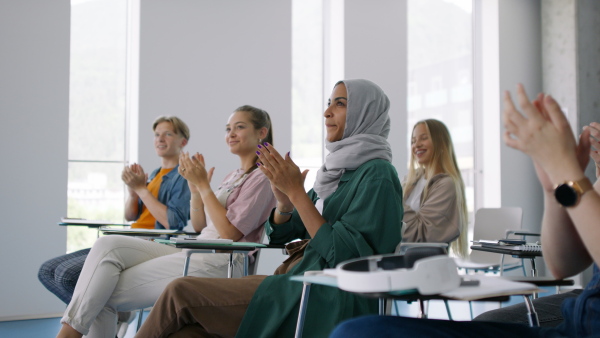 Group of university students clapping teacher for amazing presentation, lesson in classroom.