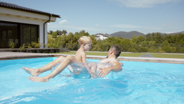 A little boy having fun with his father in inflatable ring in the pool.