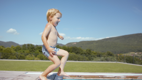 A little boy having fun and jumping into pool.