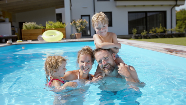 A beautiful family having fun together in the pool, looking at camera.