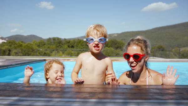 A beautiful family having fun together in the pool, looking at camera.