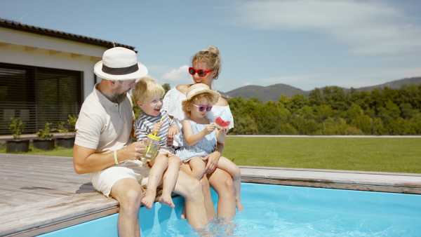 A beautiful family sitting on the edge of the pool and having fun together.