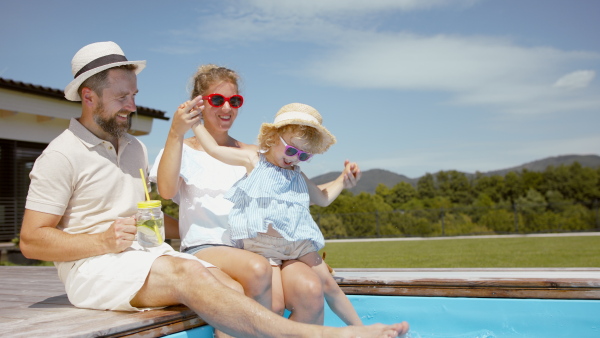 A beautiful family sitting on the edge of the pool and having fun together.