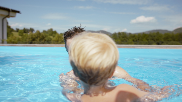 A little boy having fun with his father in the pool.