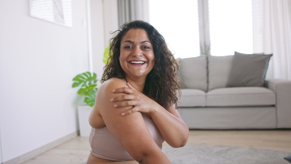 A happy beautiful young overweight woman indoors at home, looking at camera.