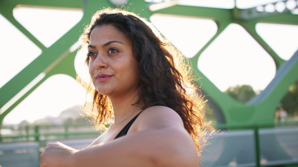 A close up of young overweight woman exercising outdoors in bridge.