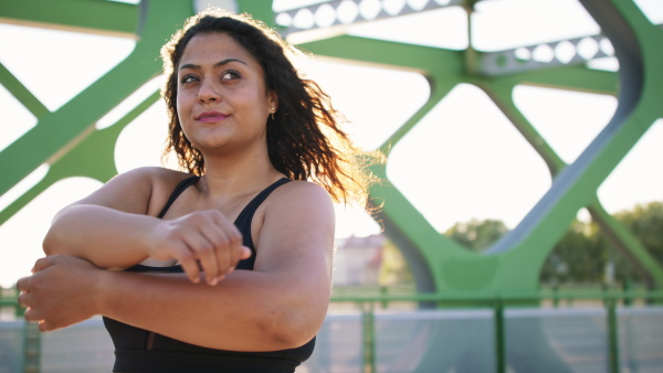 A close up of young overweight woman exercising outdoors in bridge.