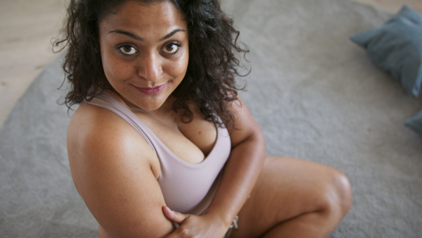 A happy beautiful young overweight woman indoors at home, looking at camera.