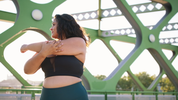 A close up of young overweight woman exercising outdoors in bridge.