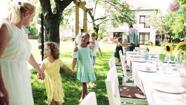 Kids on birthday party playing outdoors in garden in summer, celebration concept. Slow motion.