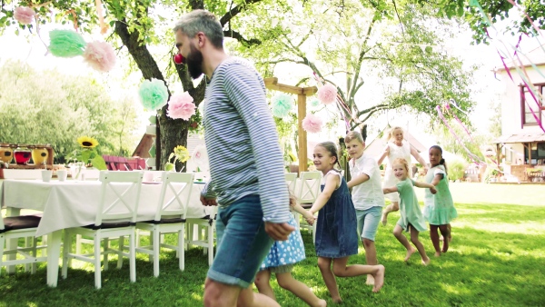 Group of kids on birthday party playing outdoors in garden in summer, celebration concept.