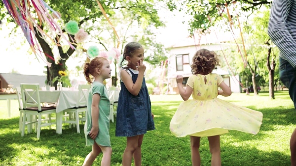 A man with small children sitting on ground outdoors in garden in summer, playing. Slow motion.