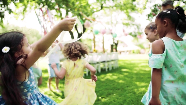 Small children playing outdoors on garden party in summer. Slow motion.