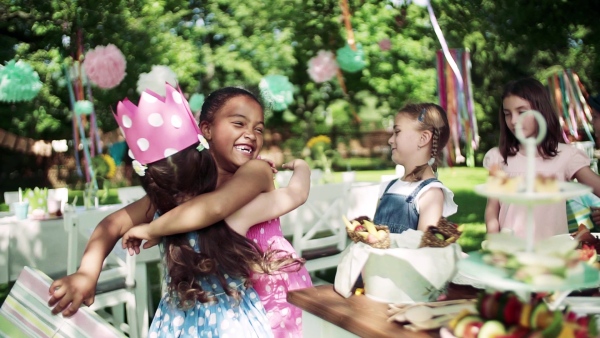 A birthday party of small girl outdoors in garden in summer, celebration concept. Slow motion.