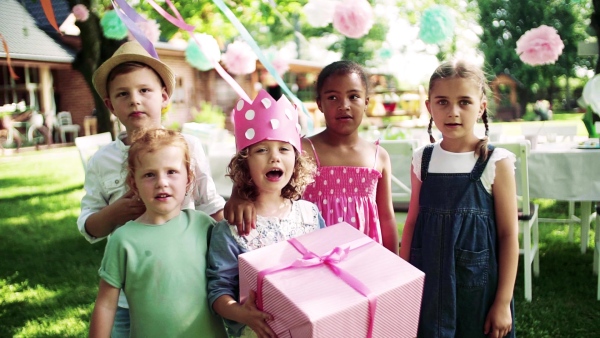 A birthday party of small girl outdoors in garden in summer, celebration concept. Slow motion.