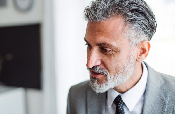 A close-up of mature businessman standing in an office. A copy space.