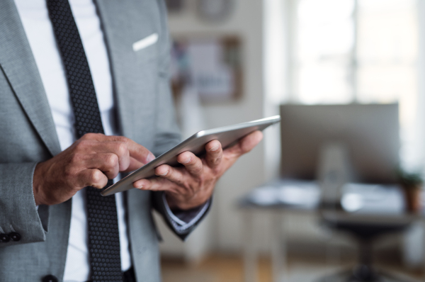 A midsection of unrecognizable businessman in an office, using tablet. Copy space.