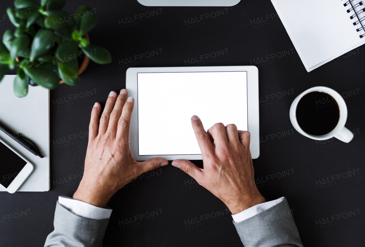 A top view of male hands holding tablet on a desk. A copy space.