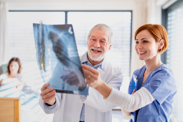 Doctors standing in hospital room, examining lungs X-ray.