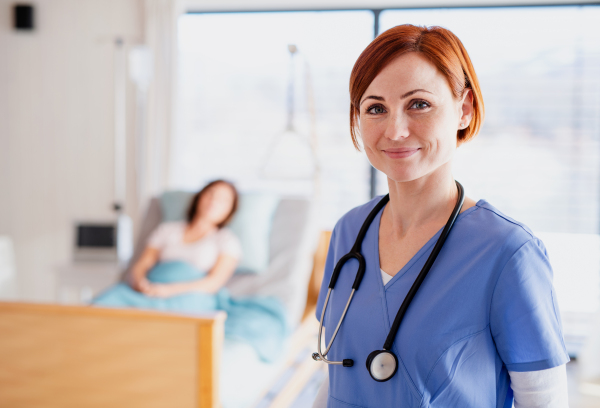 A doctor or nurse standing in hospital room, looking at camera. Copy space.