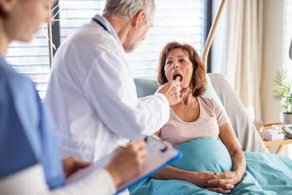 A senior male doctor examining a woman patient in hospital.