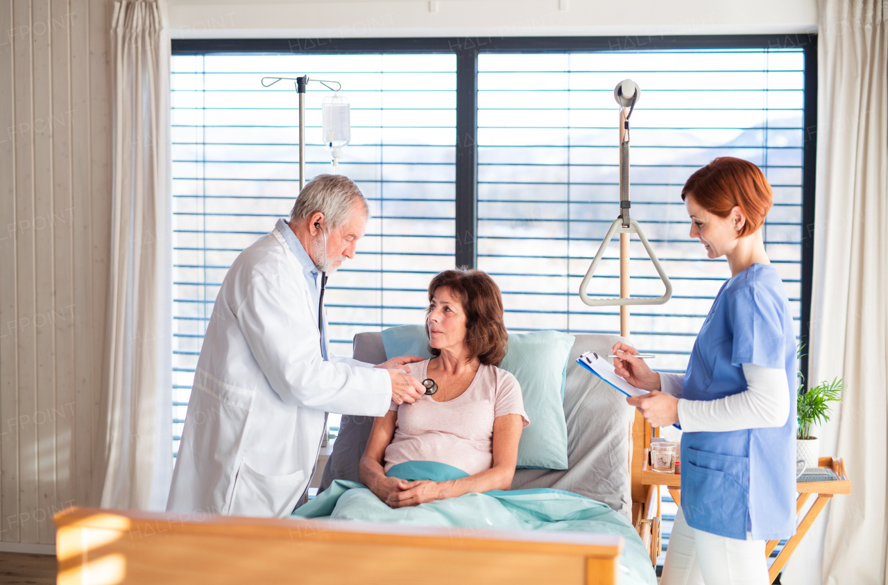 A senior doctor and nurse examining a woman patient in hospital.