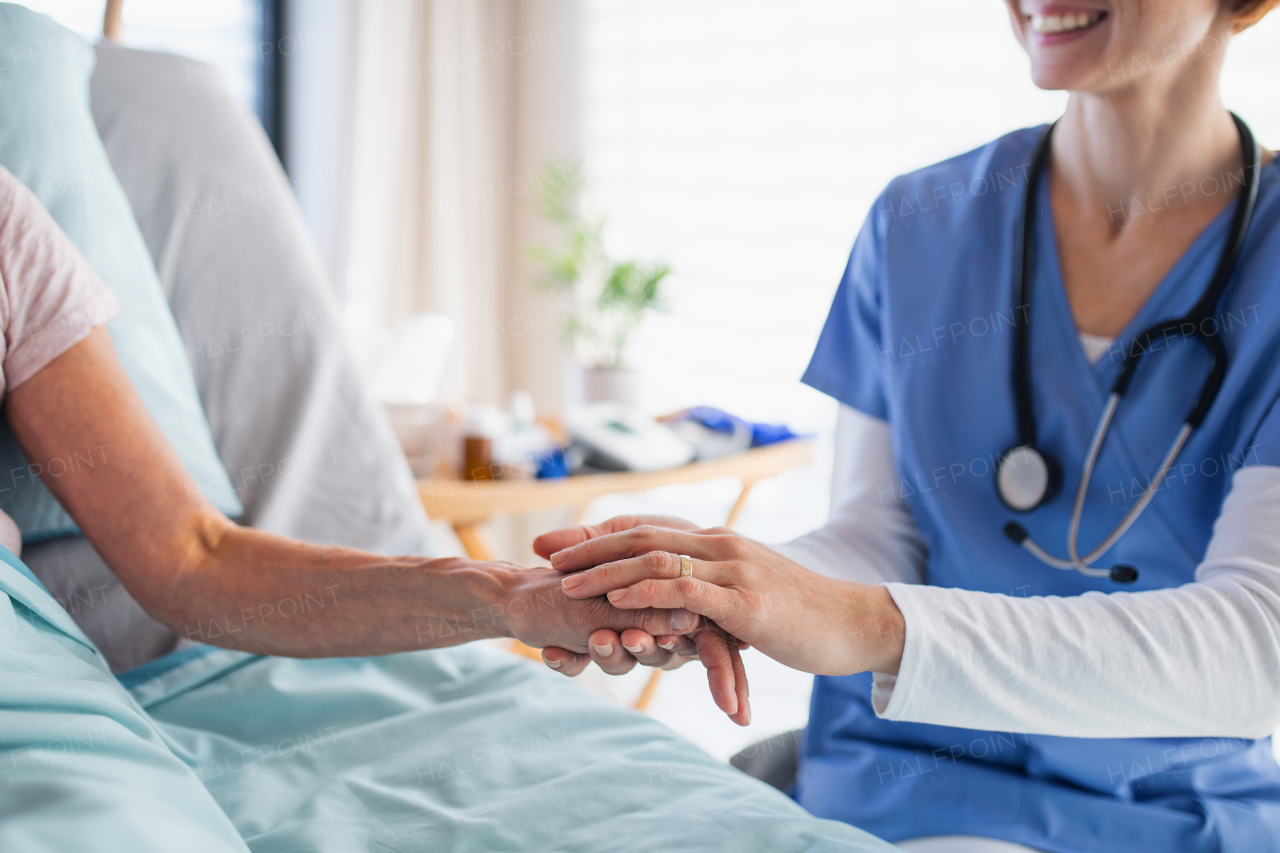 Unrecognizable friendly female doctor examining patient in bed in hospital.