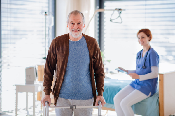 Female doctor and senior patient with walking frame in hospital, looking at camera.