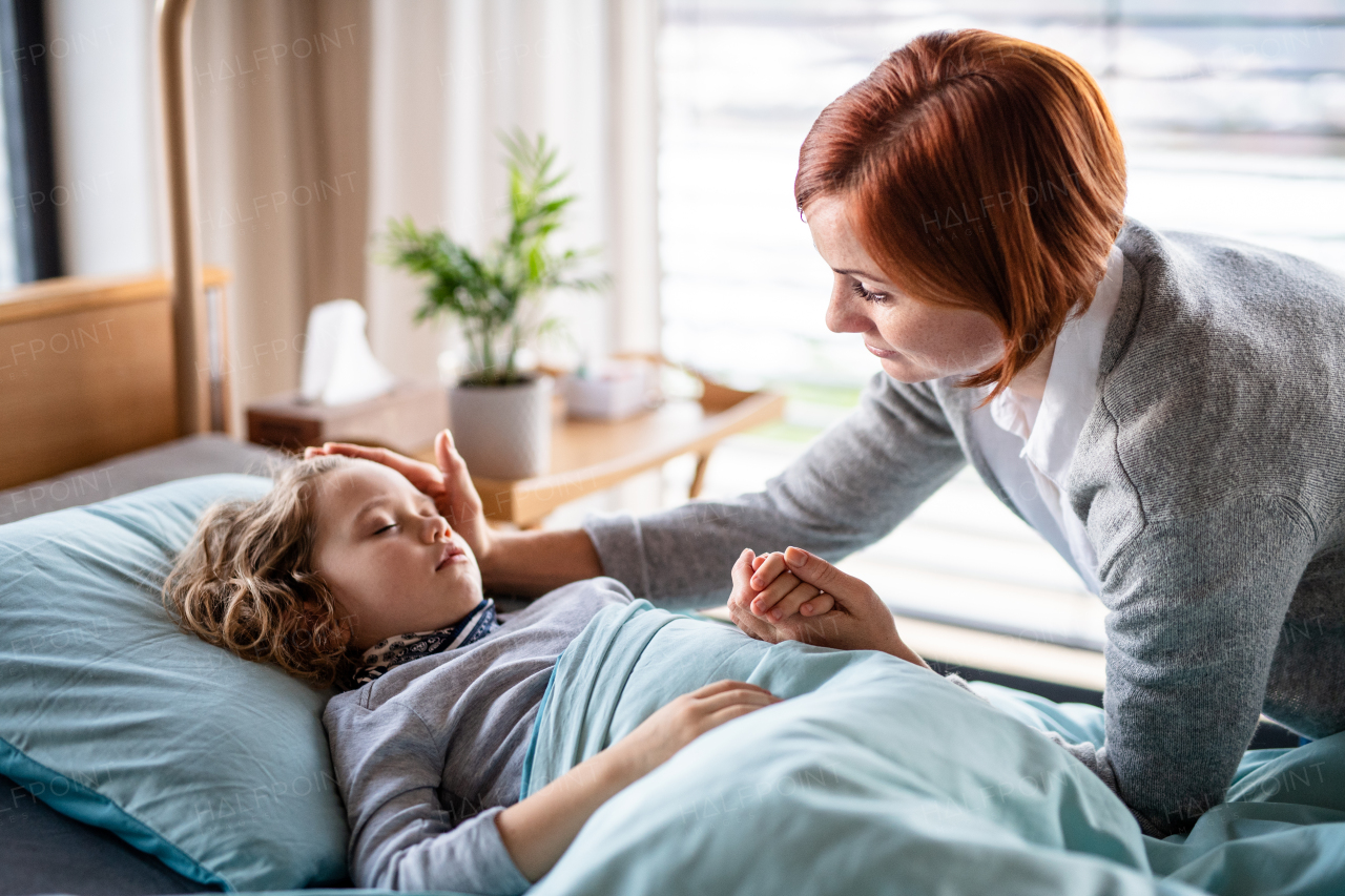 Caring mother visiting sleeping small girl daughter in bed in hospital.