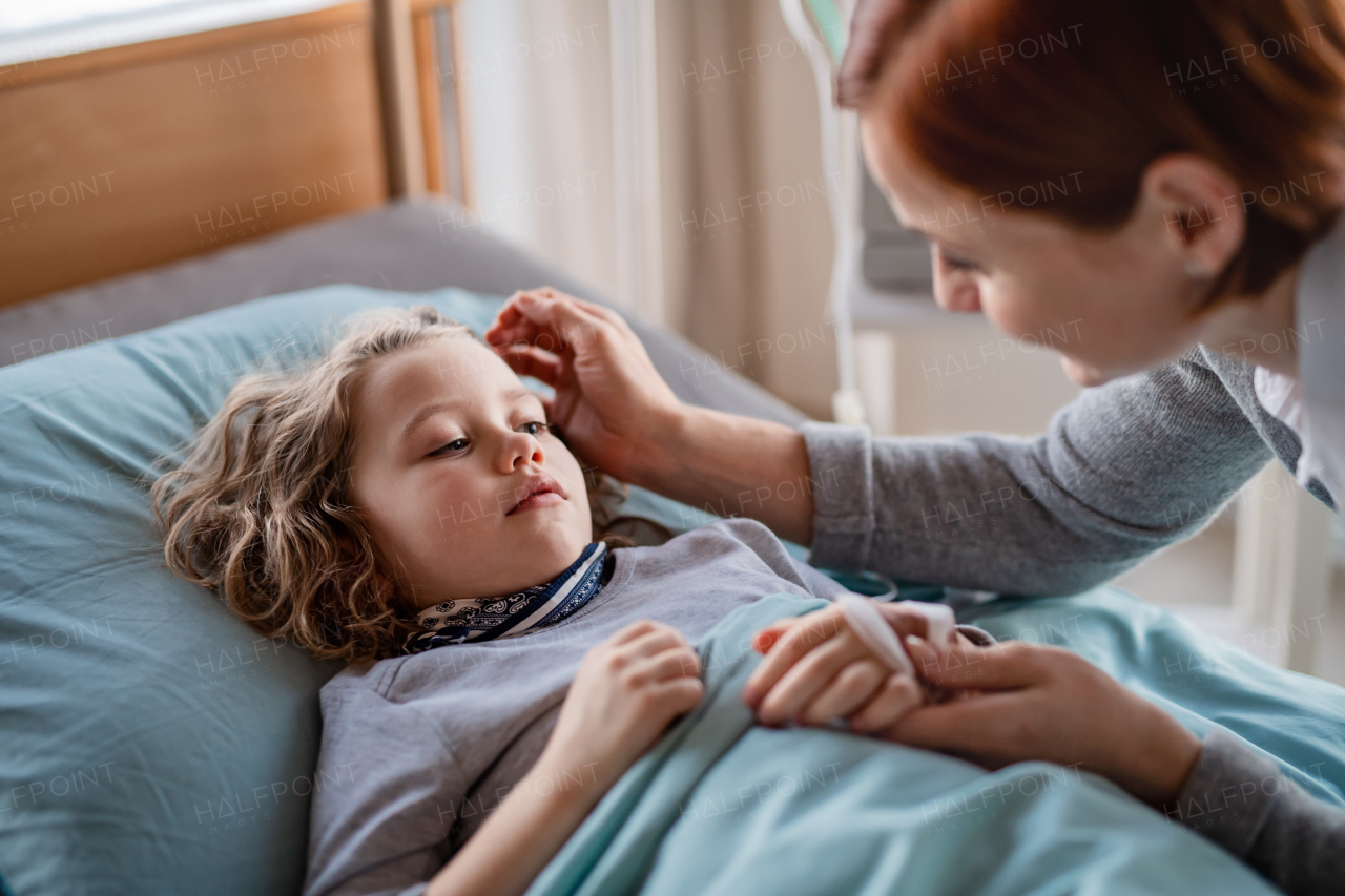 A caring mother visiting small girl daughter in bed in hospital.