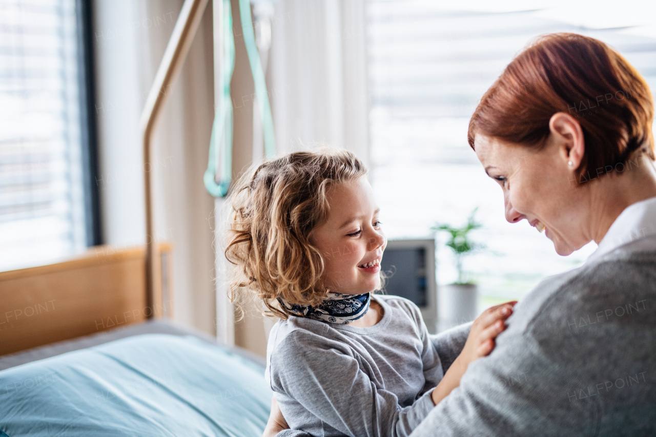 Caring mother visiting small girl daughter in bed in hospital. Copy space.