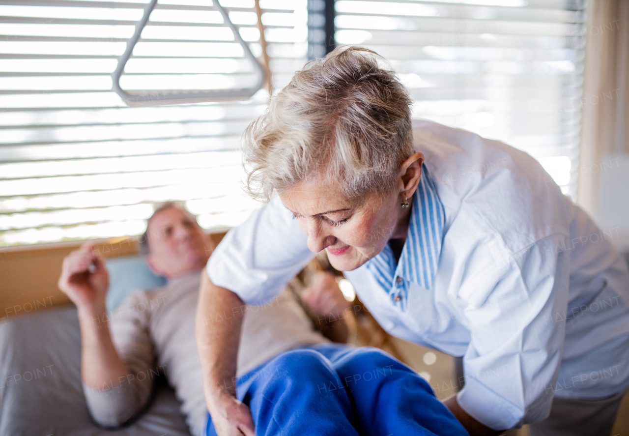 A healthcare worker helping paralysed senior patient in wheelchair in hospital.