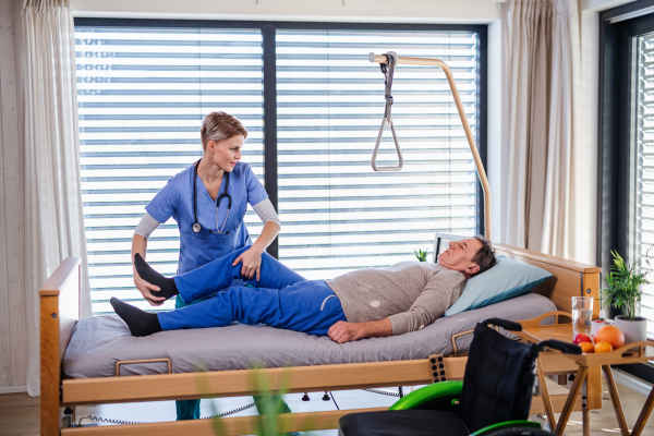 A healthcare worker and senior patient in hospital, physiotherapy concept.