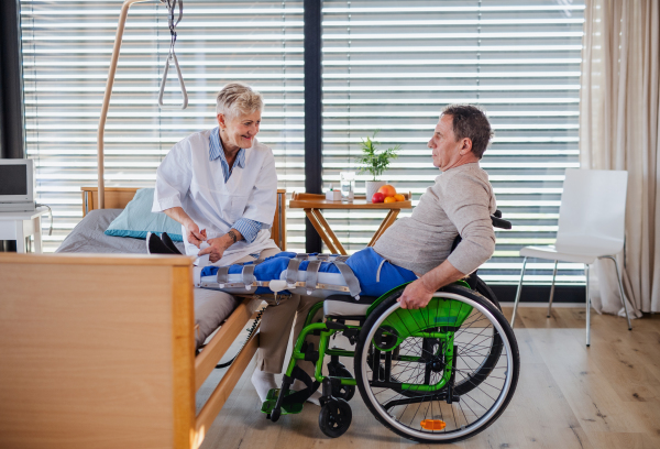 A healthcare worker and man paralysed senior patient in hospital, applying orthosis.