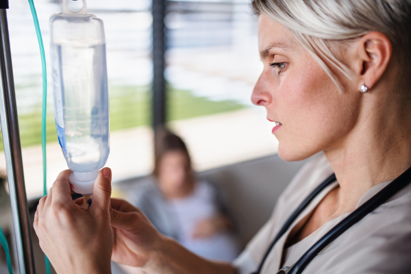 A side view of nurse preparing IV drip in hospital or at home.